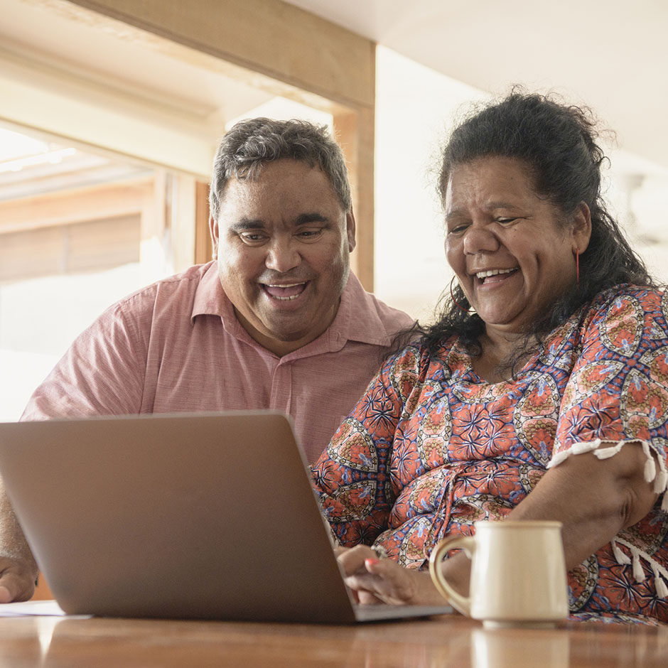 Indigenous Australian man and woman using computer and smiling side by side